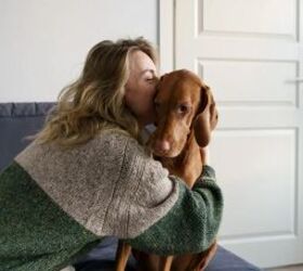 how to introduce a new pup without making your resident dog jealous, Woman cuddling a dog image via Canva